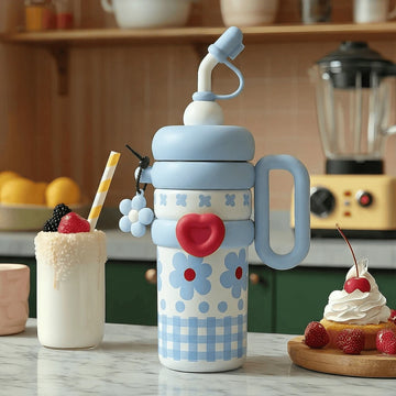 A colourful blue insulated thermos flask with floral patterns on a kitchen counter with a milkshake and desert